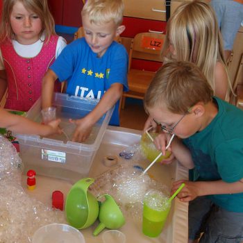 Kinder produzieren mit Strohhalmen Schaumblasen