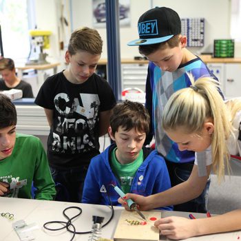 Technik, Zukunft in Bayern – Schülergruppe beim Löten mit einer Ausbilderin