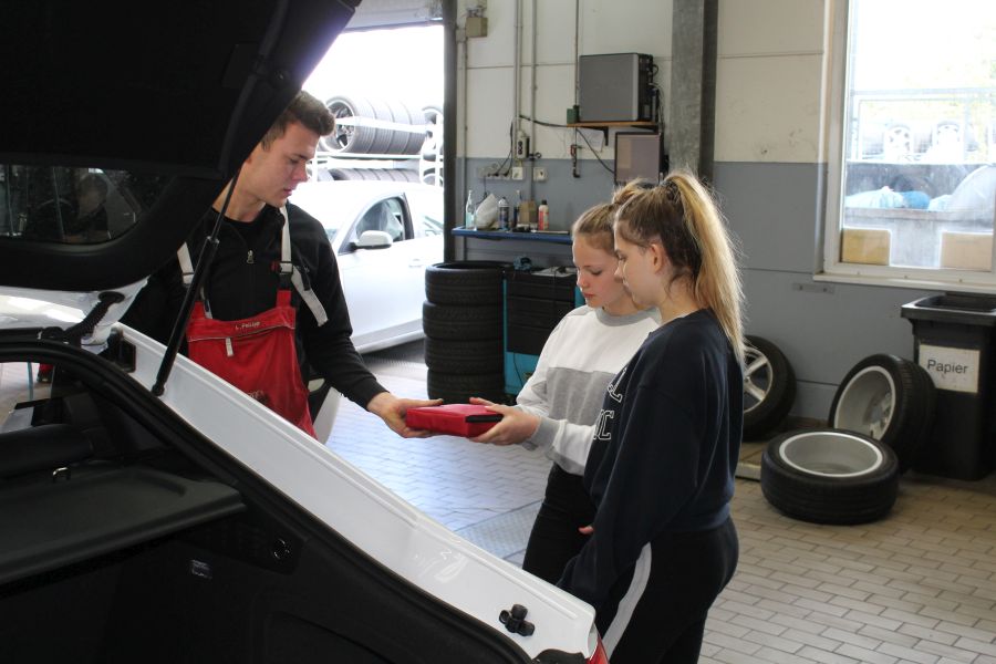 2 junge Mädchen mit einem Mechaniker in der Autowerkstatt