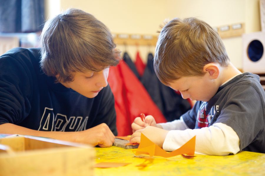 Ein Junge bastelt im Kindergarten mit einem Kindergartenkind