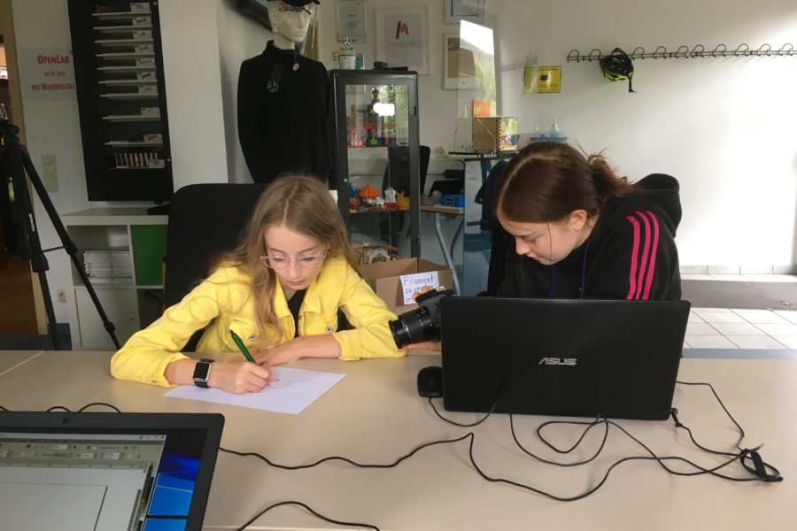 Laura entwickelt im FabLab ein Motiv für die Stickmaschine. Ihre Schwester filmt und fotografiert sie dabei.