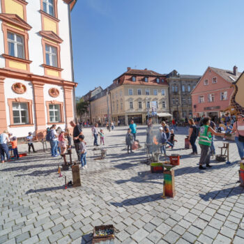 Kinder spielen im Ehrenhof der Stadt Bayreuth an Stationen des Spielmobils Bayreuth und von wundersam anders