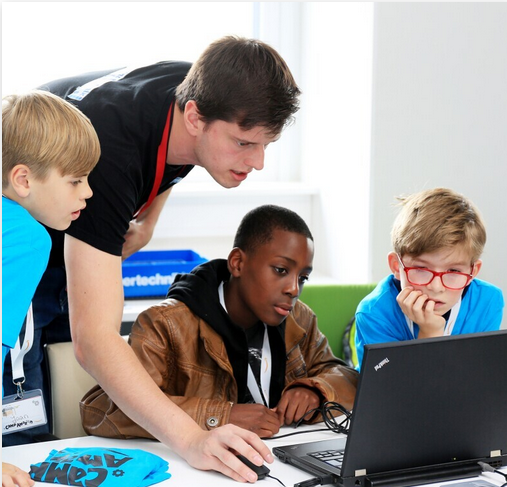 Jugendliche und ein Betreuer sitzen vor einem Laptop