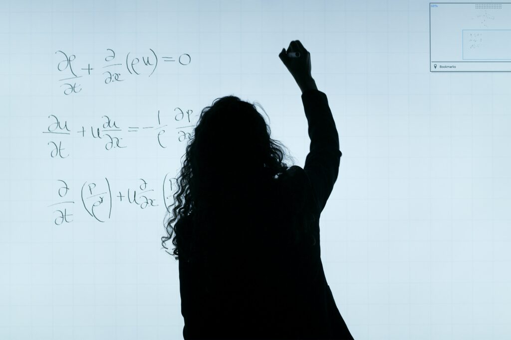 Frau schreibt mathematische Formeln auf ein Whiteboard