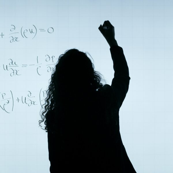 Frau schreibt mathematische Formeln auf ein Whiteboard