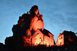 Felsen von Tüchersfeld bei Nacht, davor ist das alte Fachwerkhaus des Museums zu sehen